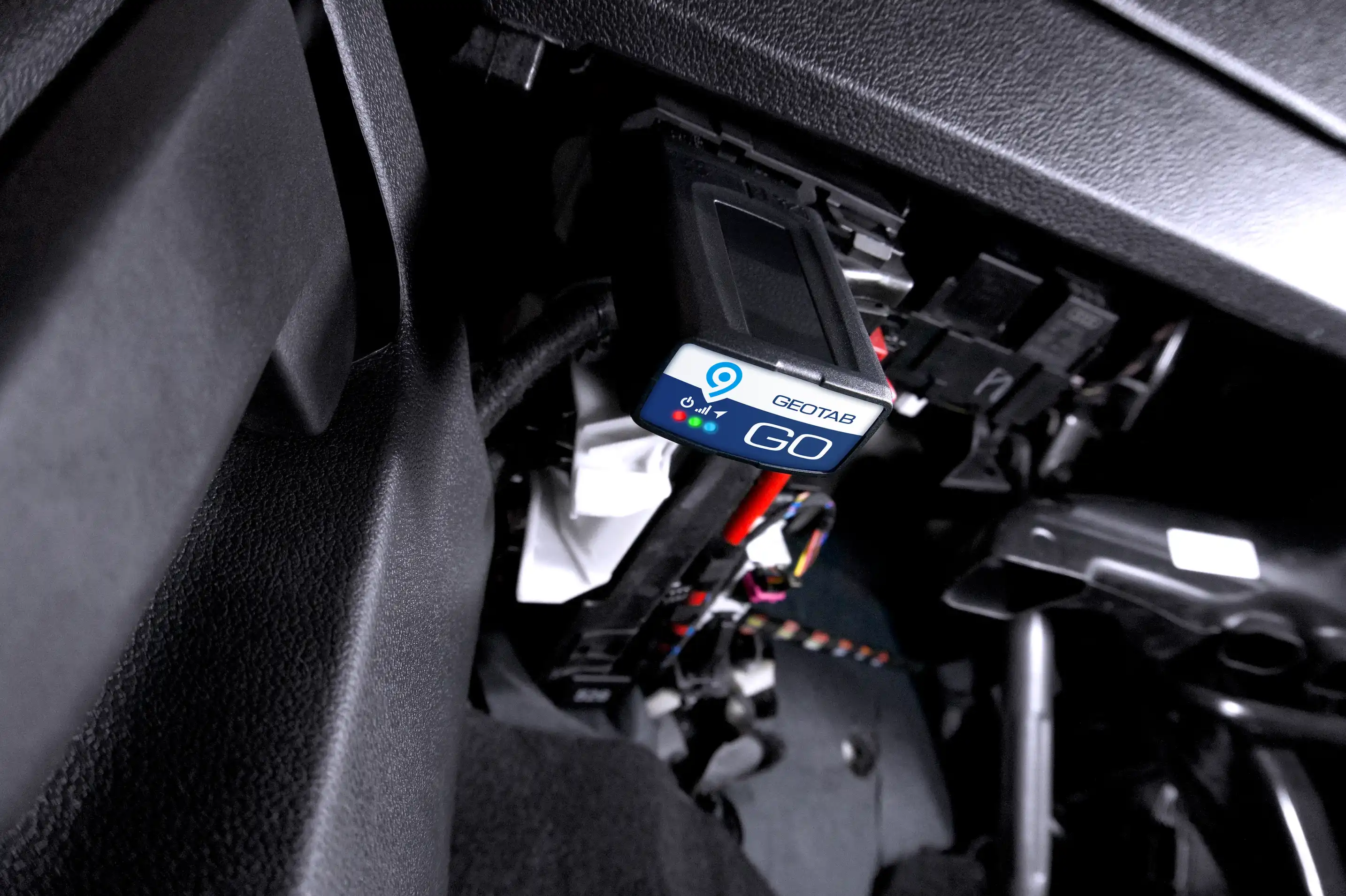 A close-up of a Geotab GO device installed under a vehicle's dashboard, showcasing easy integration for fleet tracking.